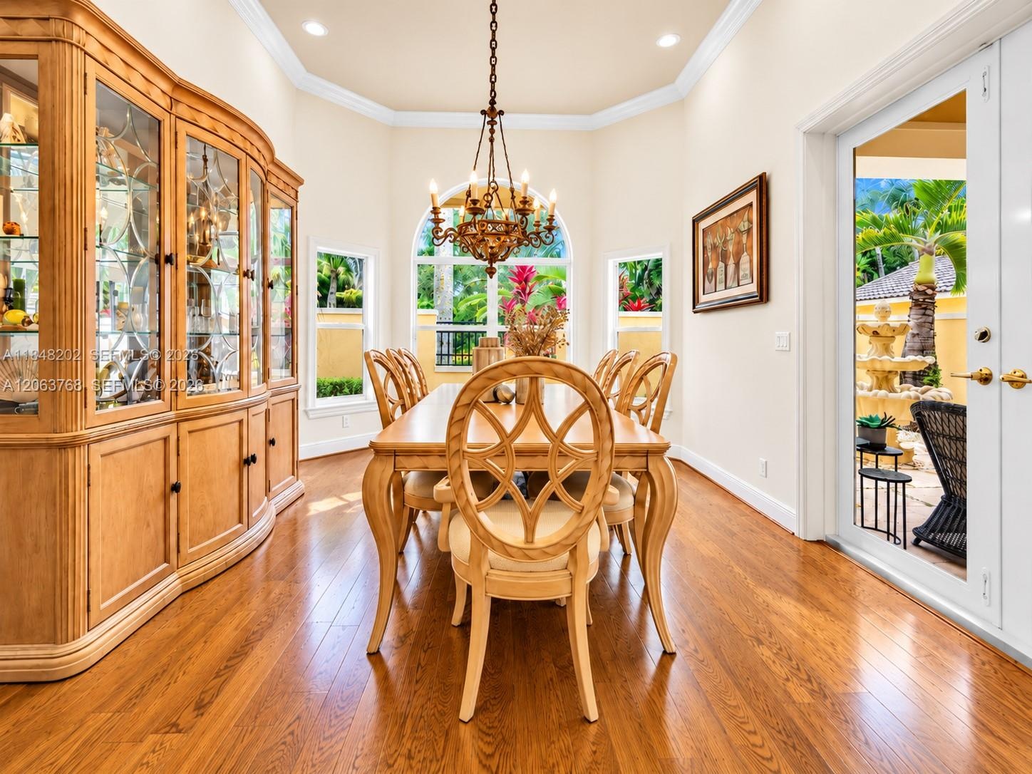Elegant dining room showcasing warm wood-finish flooring, a decorative ship's wheel dining table with coordinating chairs, and a coffered ceiling with