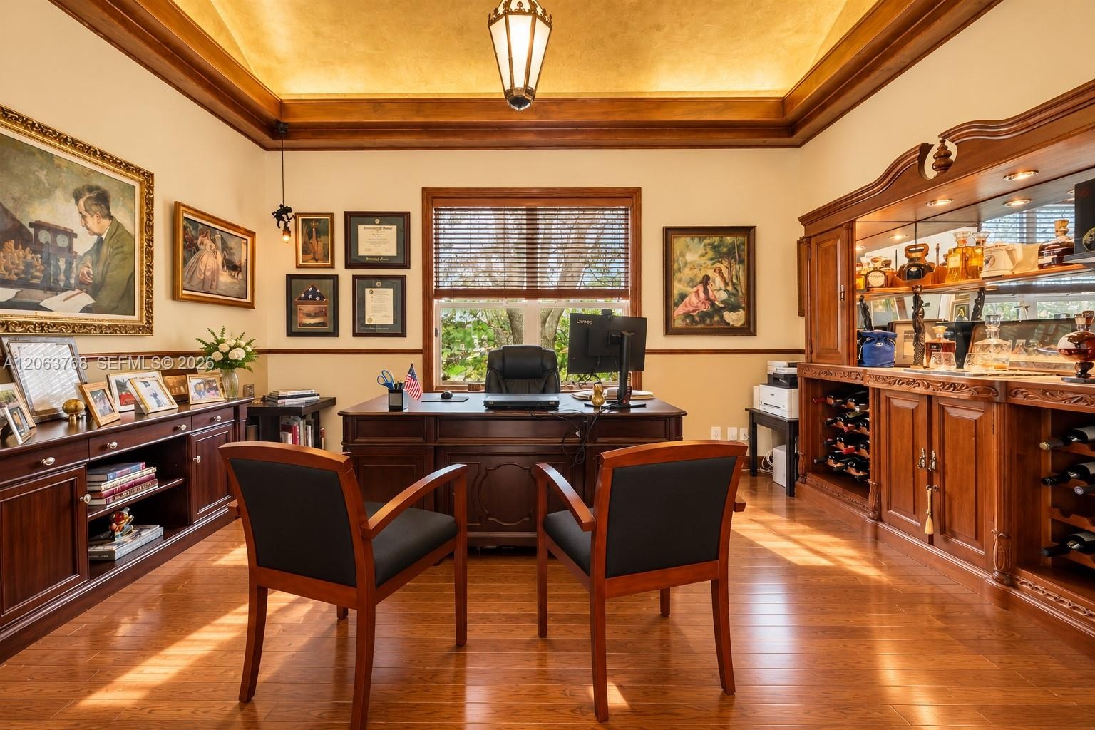 Tray ceiling with crown molding, wood-finish flooring, custom built-in cabinetry, integrated wine storage, and pendant lighting