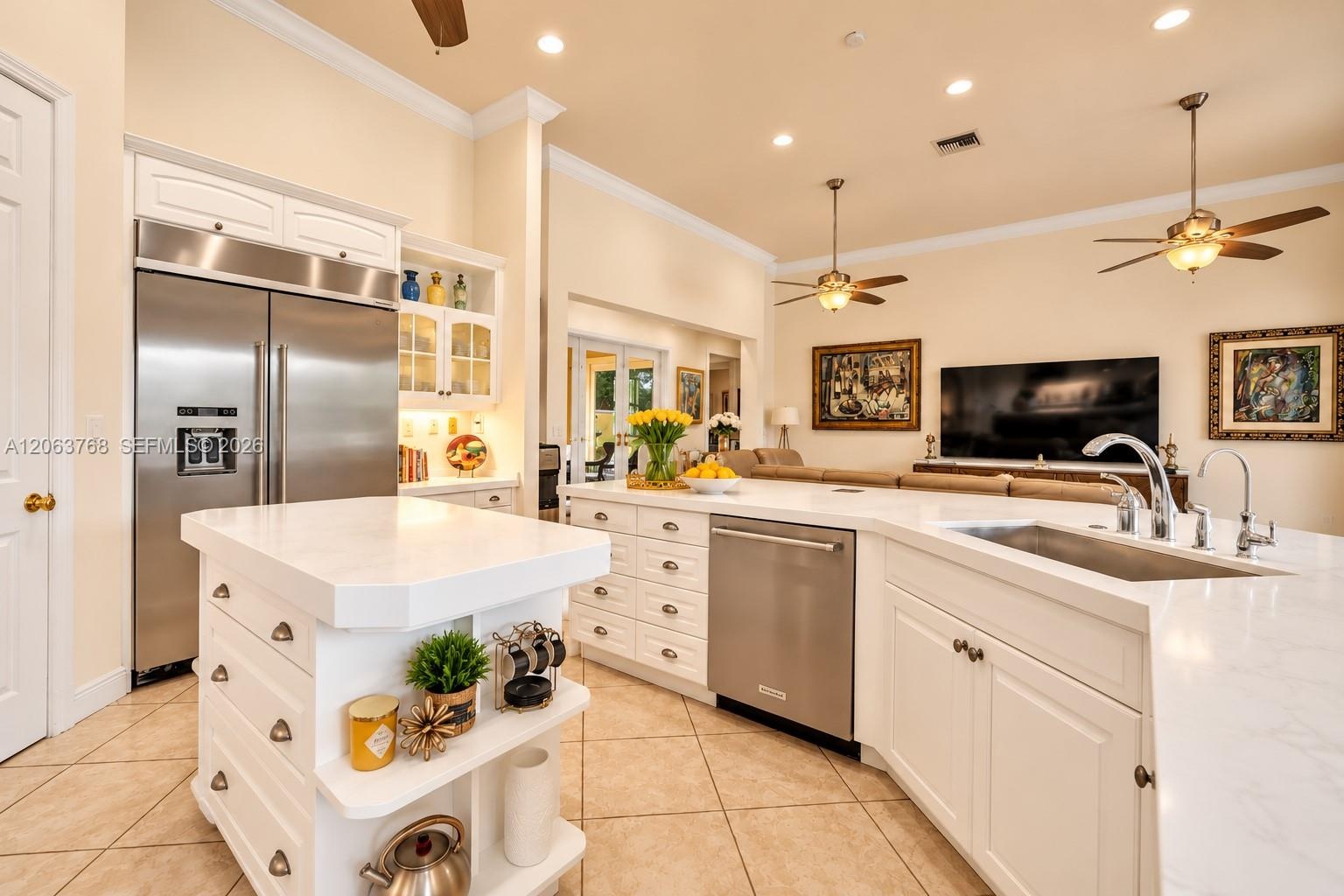 Kitchen featuring white cabinetry, stone-finish countertops, stainless steel appliances, a center island with built-in storage, and tile flooring
