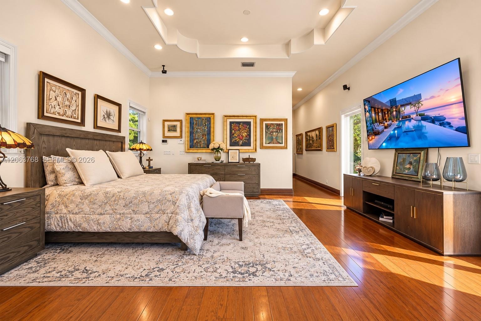 Tray ceiling with recessed lighting, wood-finish flooring, and wall-mounted electrical fixtures