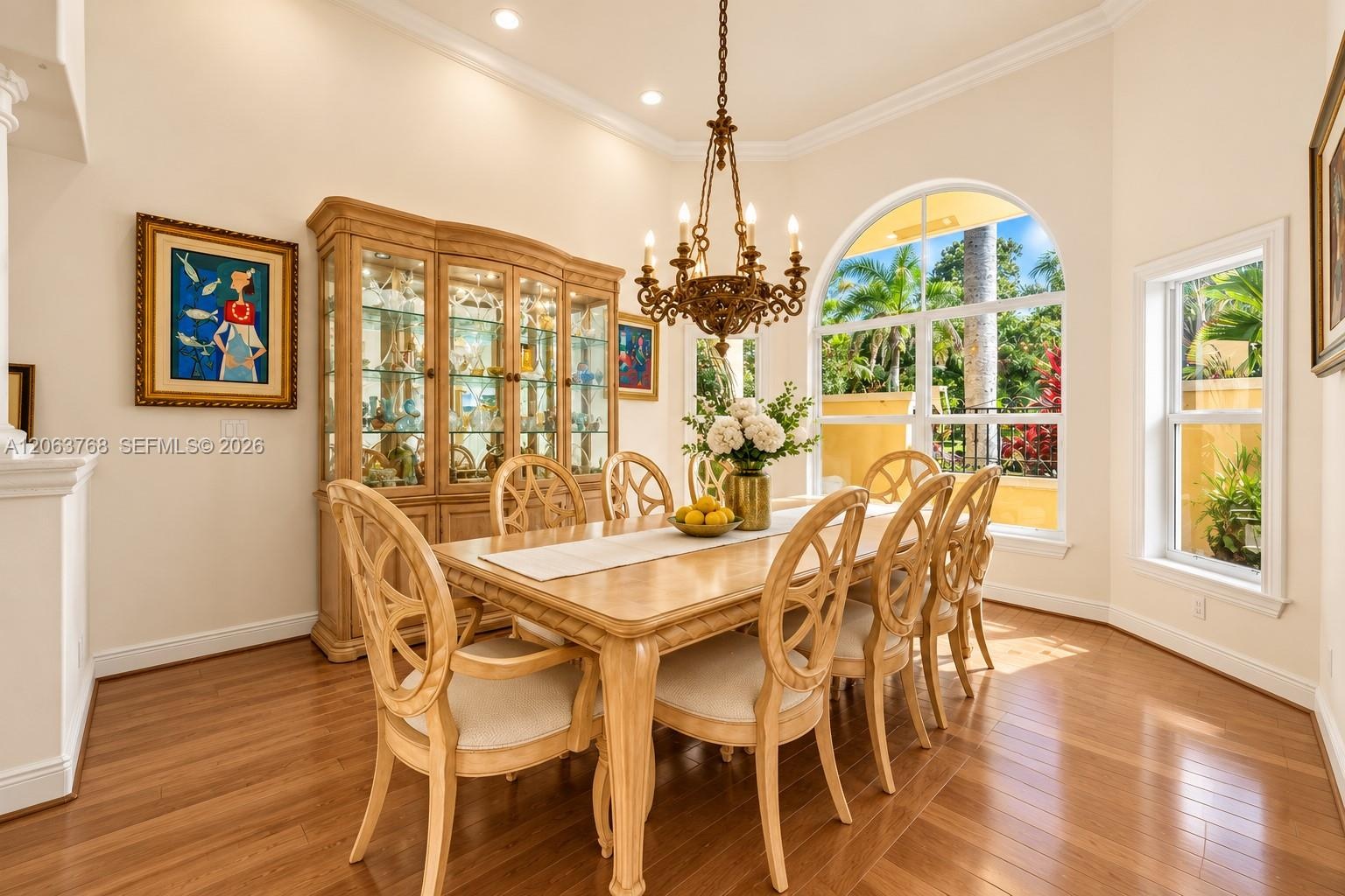 Dining area featuring wood-finish flooring, vaulted ceilings, recessed lighting, a decorative chandelier, and an arched window