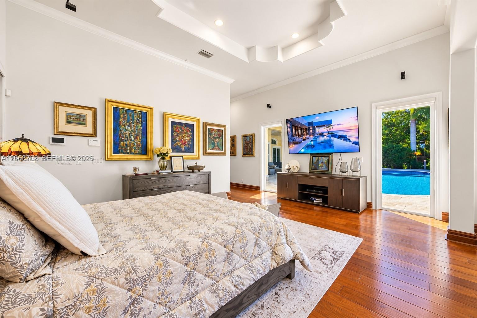 Tray ceiling with recessed lighting, wood-finish flooring, and glass-paneled door opening to a pool area