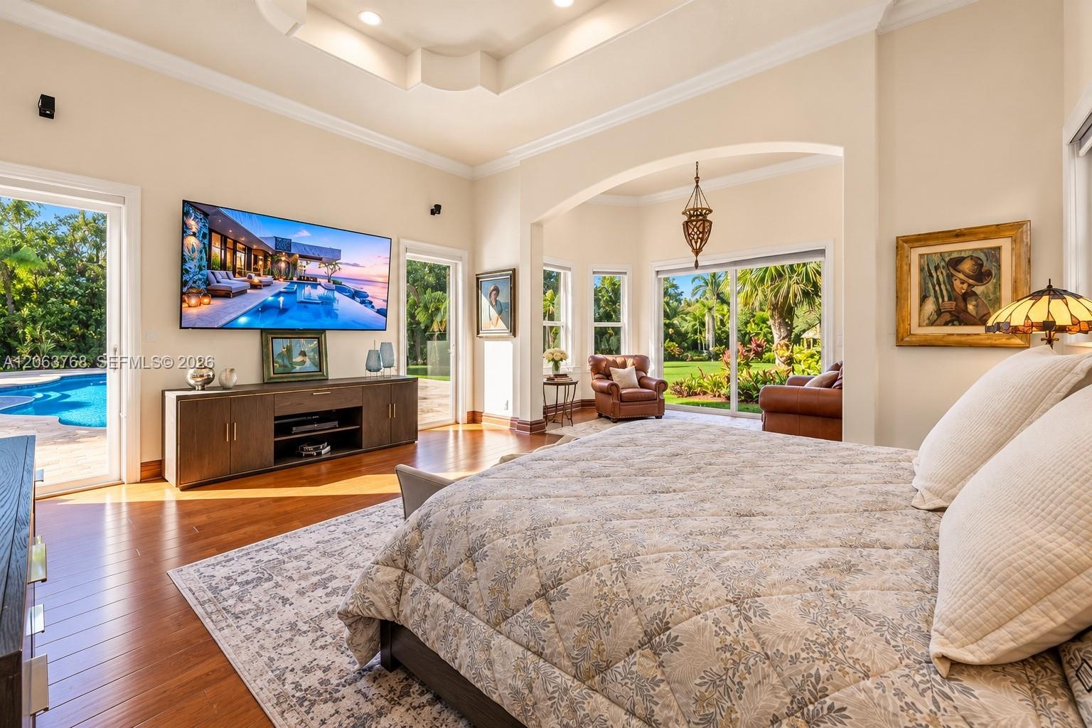 Tray ceiling with recessed lighting, wood-finish flooring, architectural archway, and two sets of sliding glass doors