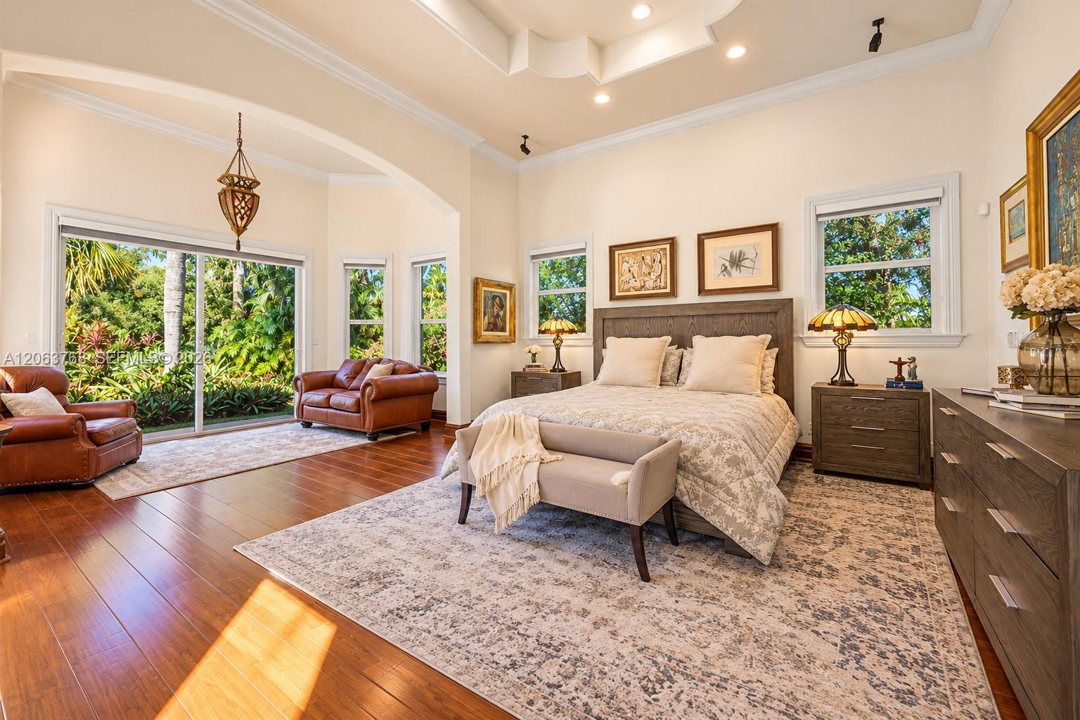Tray ceiling with recessed lighting, wood-finish flooring, and large sliding glass doors providing outdoor access