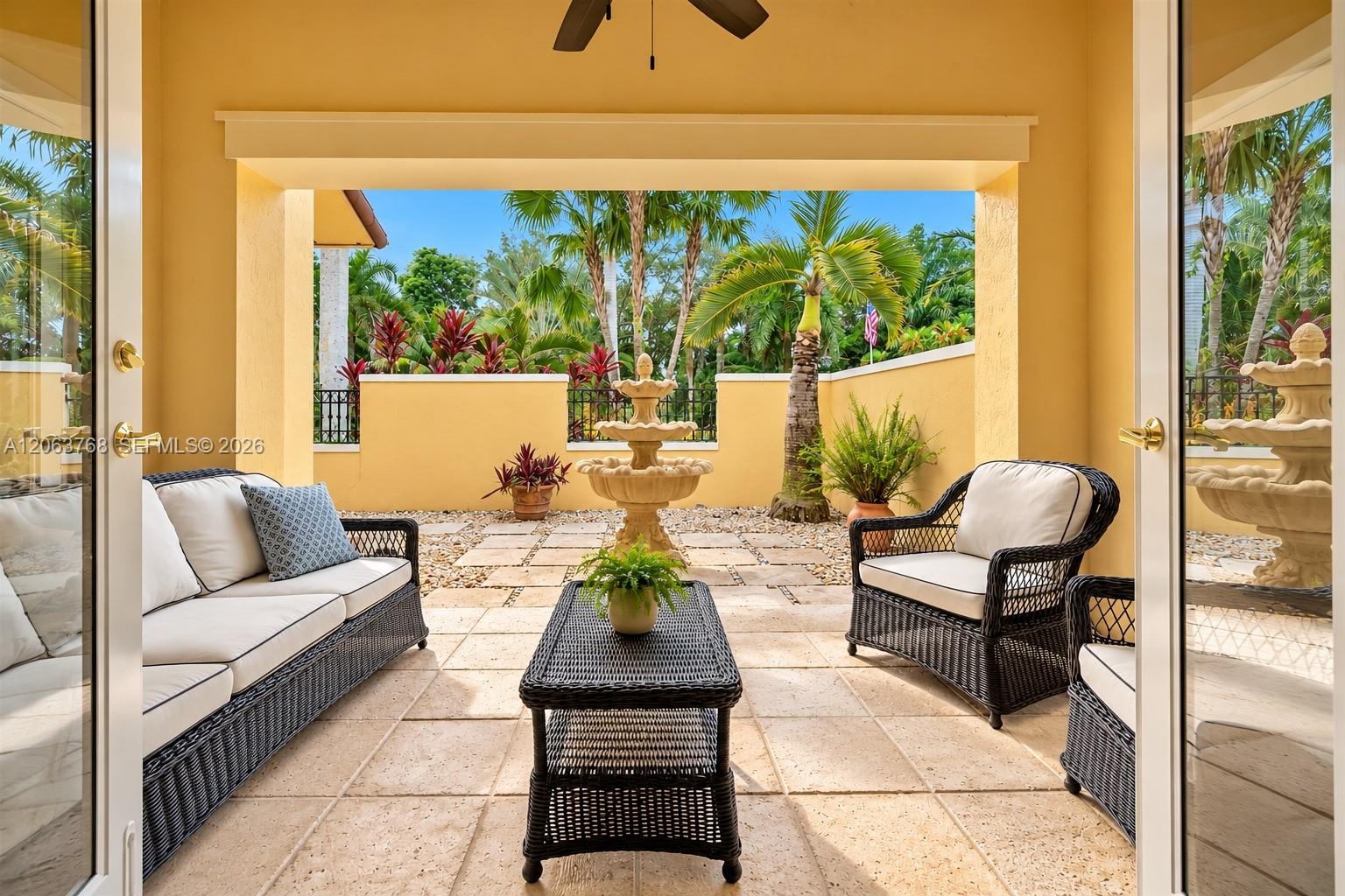 Covered patio featuring stone-tiled flooring, a central tiered stone fountain, and perimeter walls with integrated metal railing