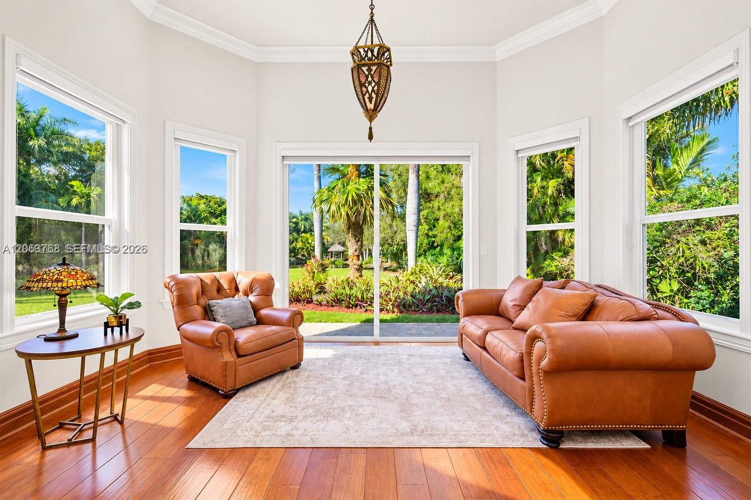 Sunroom featuring wood-finish flooring, a decorative pendant light, and multiple oversized windows providing natural illumination