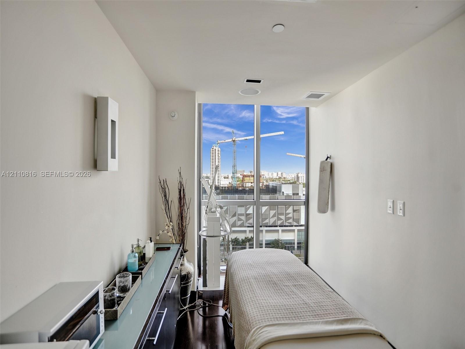 Floor-to-ceiling windows, dark wood-finish flooring, built-in cabinetry with a glass surface, recessed ceiling lighting, and wall-mounted sconce light