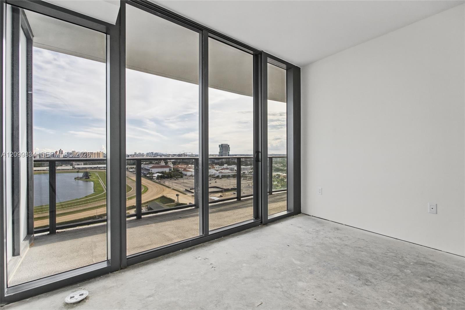 Floor-to-ceiling glass panel walls, polished concrete flooring, and private balcony with black metal railing