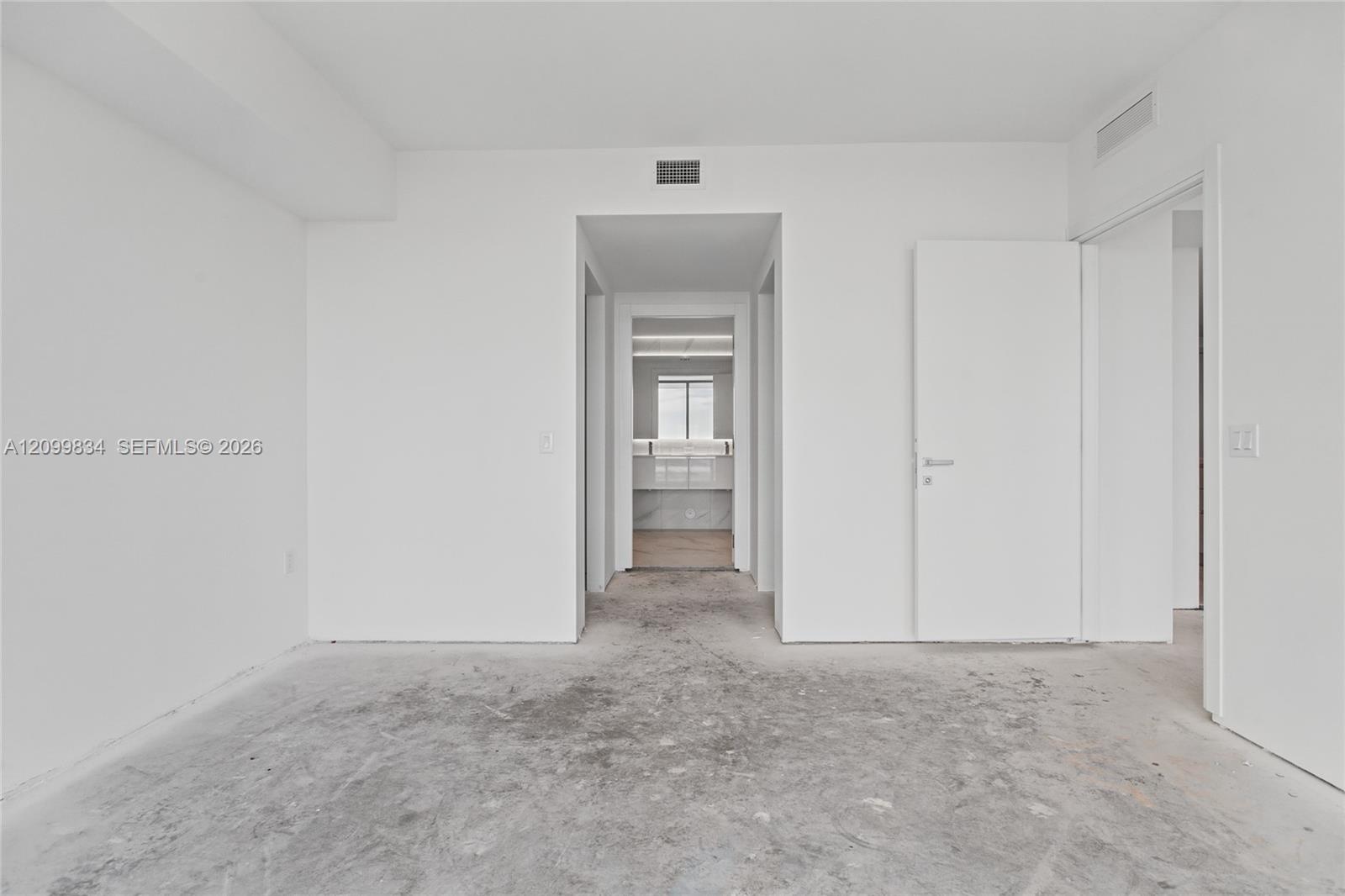 Neutral-toned interior space featuring crisp white walls, a solid-core interior door, and a pass-through doorway