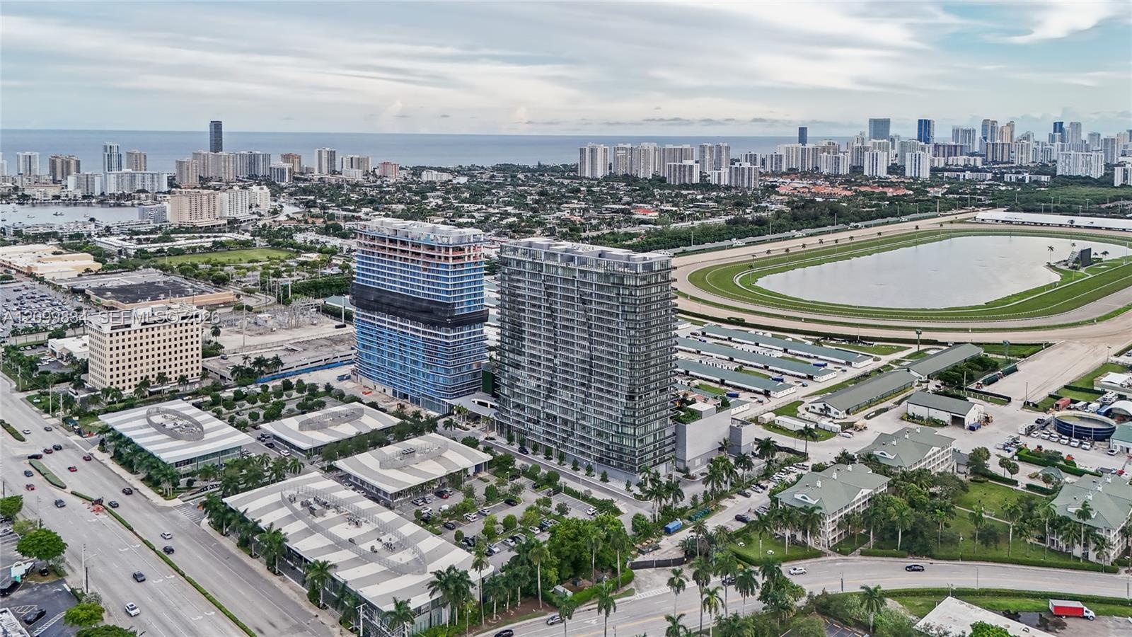 High-rise residential tower featuring a glass facade, expansive coastal horizon, and proximity to an equestrian track