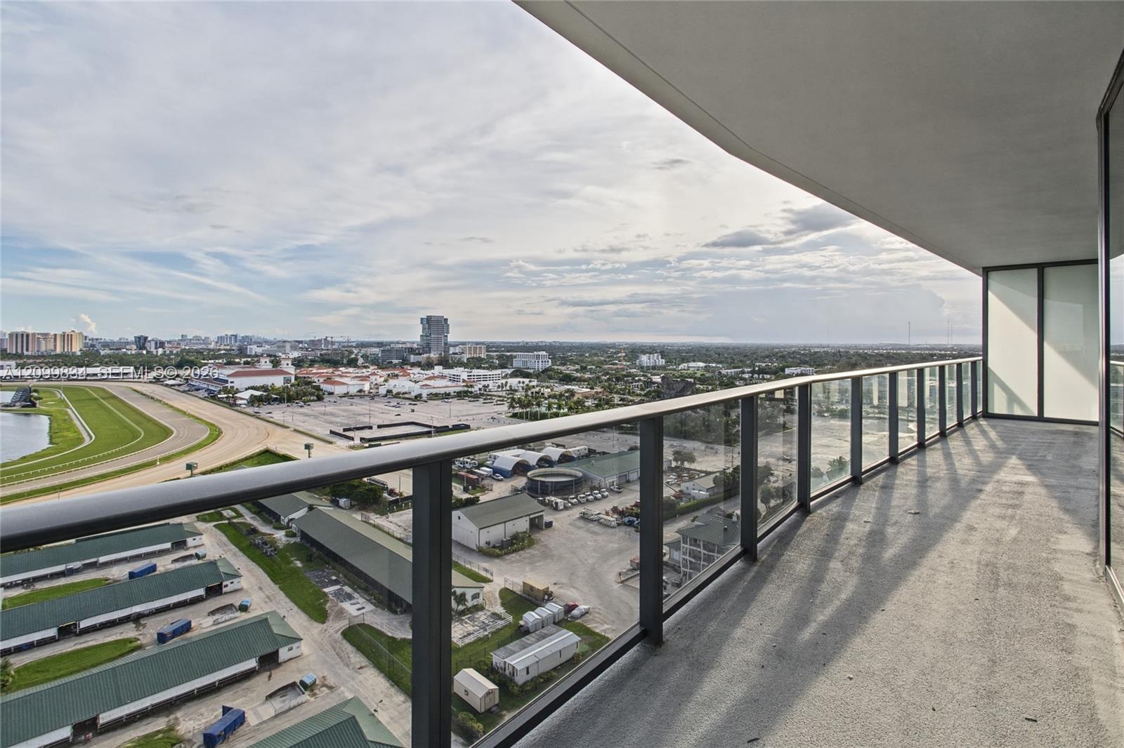 Covered balcony featuring concrete flooring and a sleek metal railing with glass panels