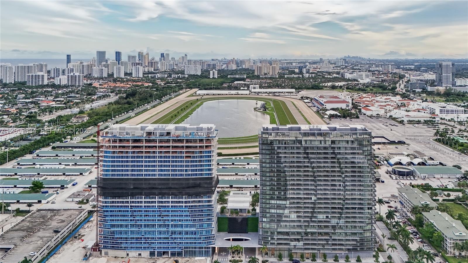 Aerial perspective featuring high-rise concrete structures positioned along a large oval racetrack and central water basin