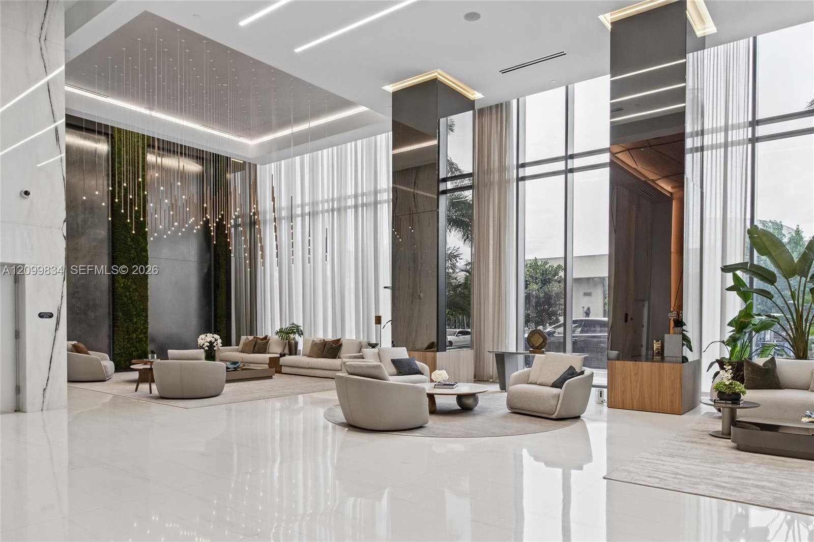 Grand lobby featuring floor-to-ceiling windows, high-gloss stone flooring, mirrored structural pillars, integrated recessed ceiling lighting, and a ve