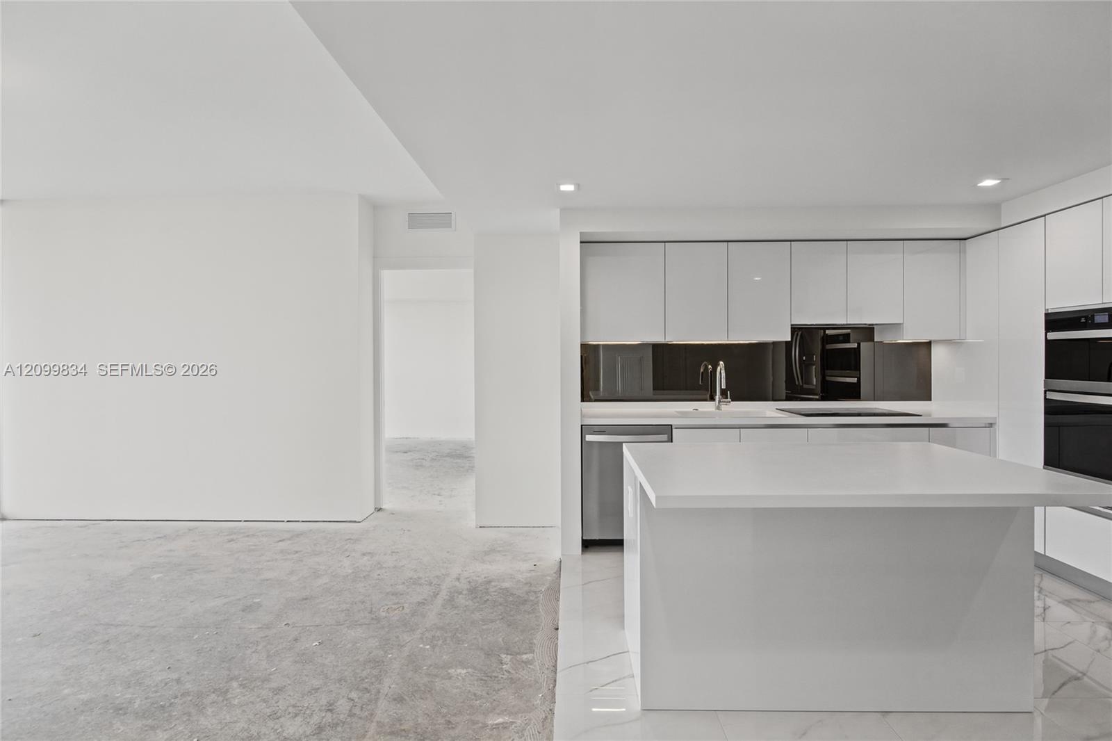 Contemporary kitchen featuring high-gloss white cabinetry, a waterfall-edge central island, integrated stainless steel appliances, a dark mirrored bac