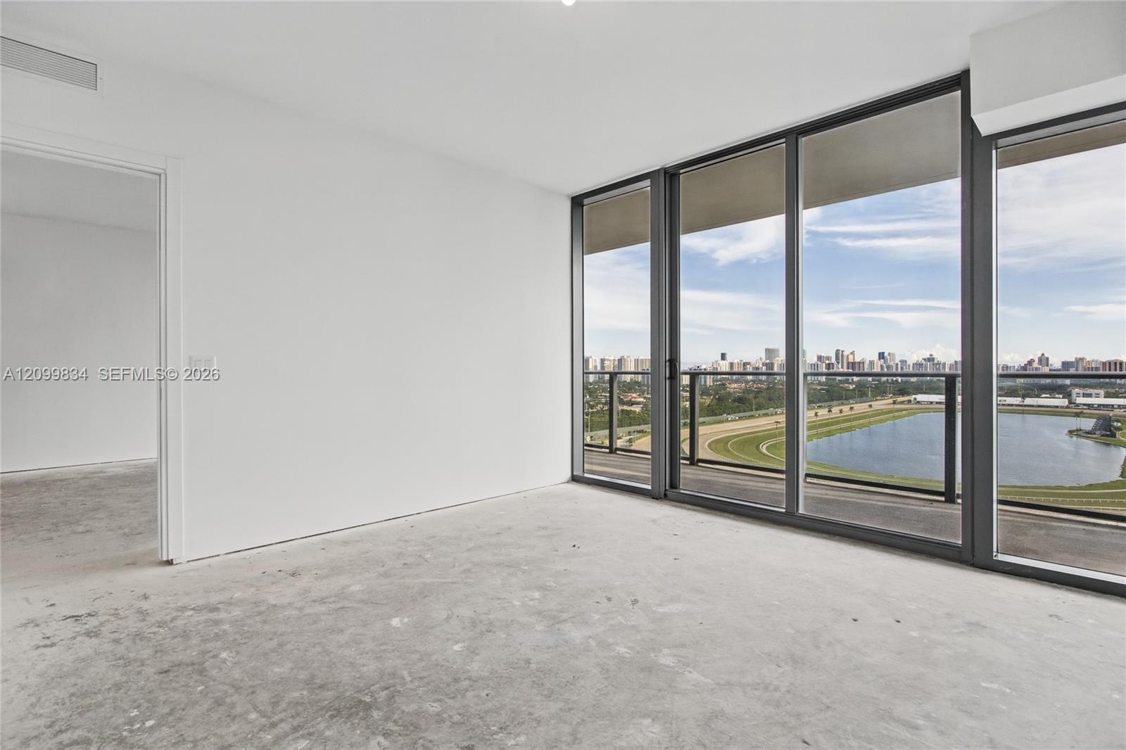Floor-to-ceiling windows with dark metal framing, concrete flooring, and access to a balcony with metallic railing
