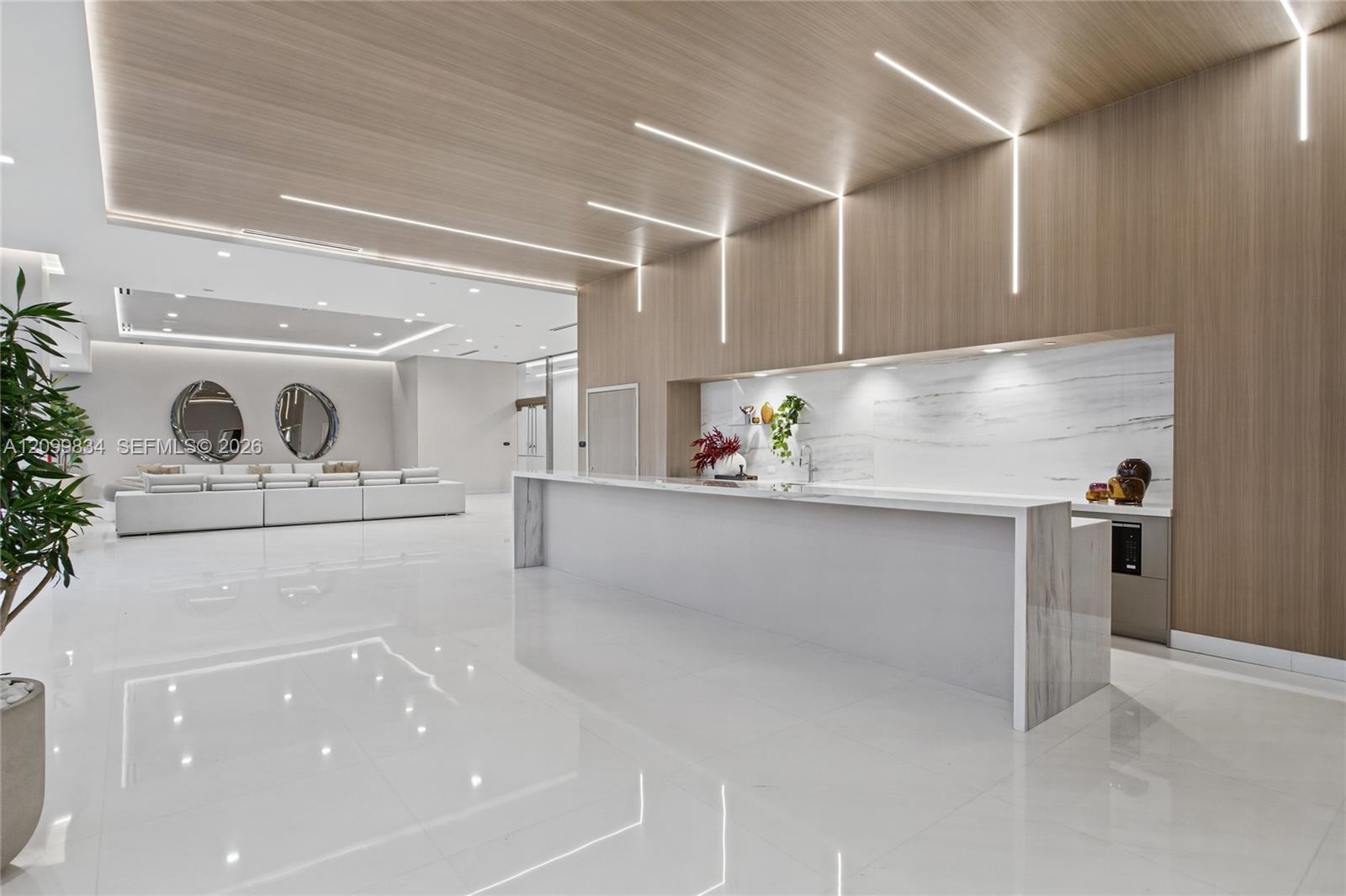 Expansive interior featuring large-format tile flooring, integrated linear LED lighting, natural wood-finish wall and ceiling paneling, and a stone-su