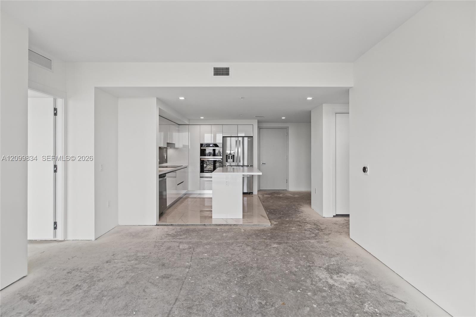 Kitchen featuring high-gloss cabinetry, stone-surfaced center island, integrated stainless steel appliances, and built-in double wall ovens