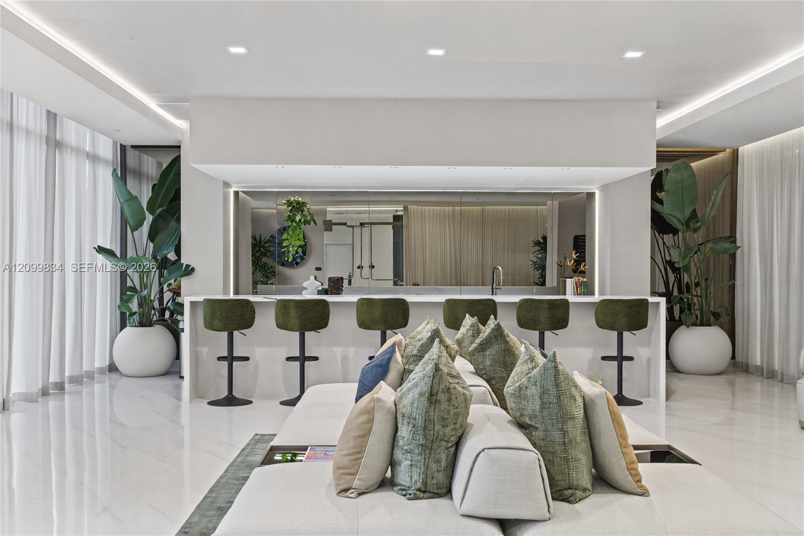 Polished stone flooring, custom wet bar with mirrored backsplash and integrated under-cabinet lighting, and recessed ceiling lighting