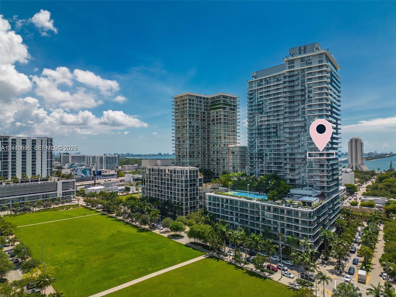 Vibrant urban skyline featuring modern high-rise residential towers with glass and metal facades, manicured green space with mature landscaping, tree-