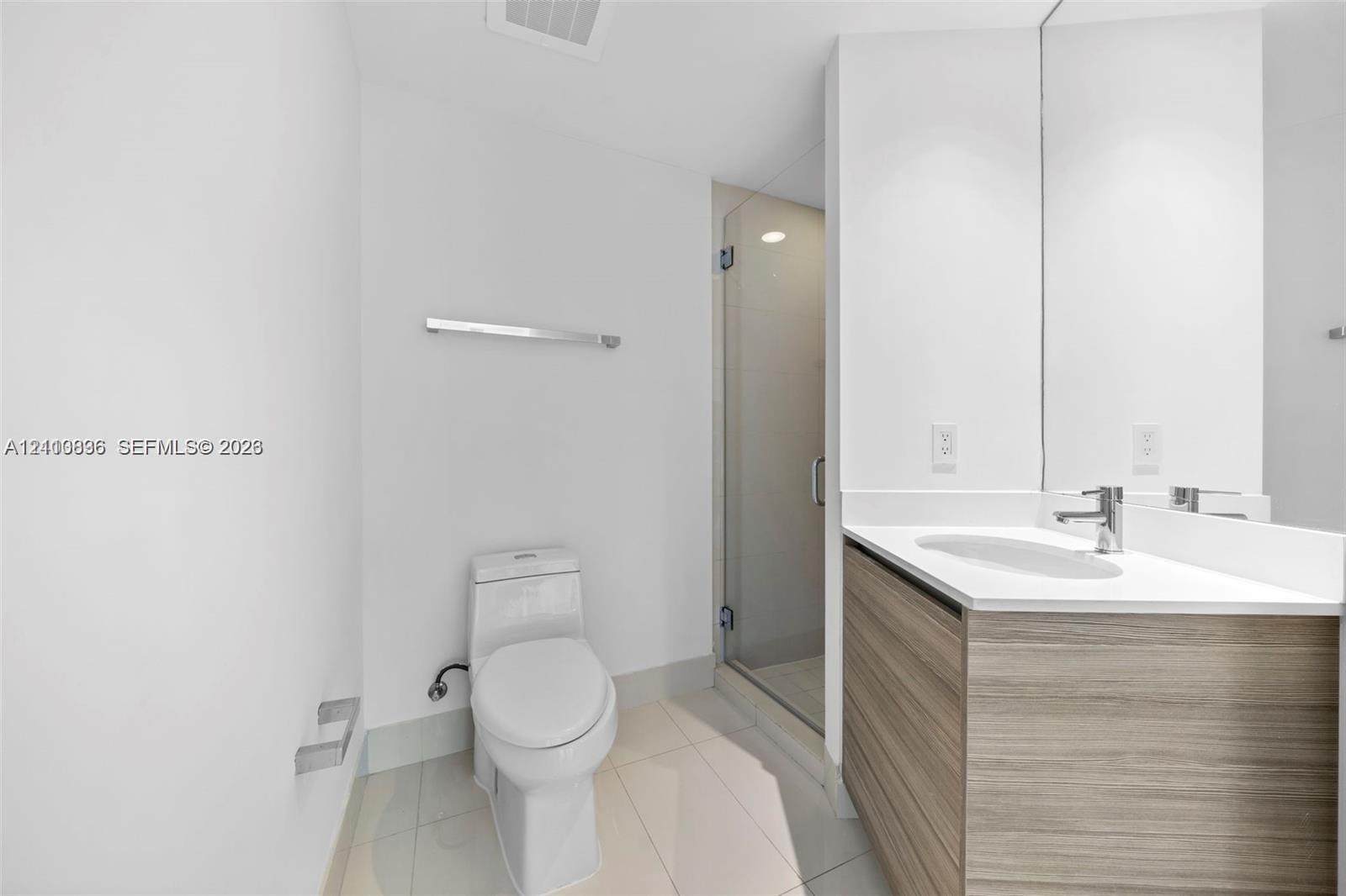Modern bathroom featuring a floating wood-finish vanity with an integrated sink and chrome faucet, white quartz countertop, large mirror with integrat