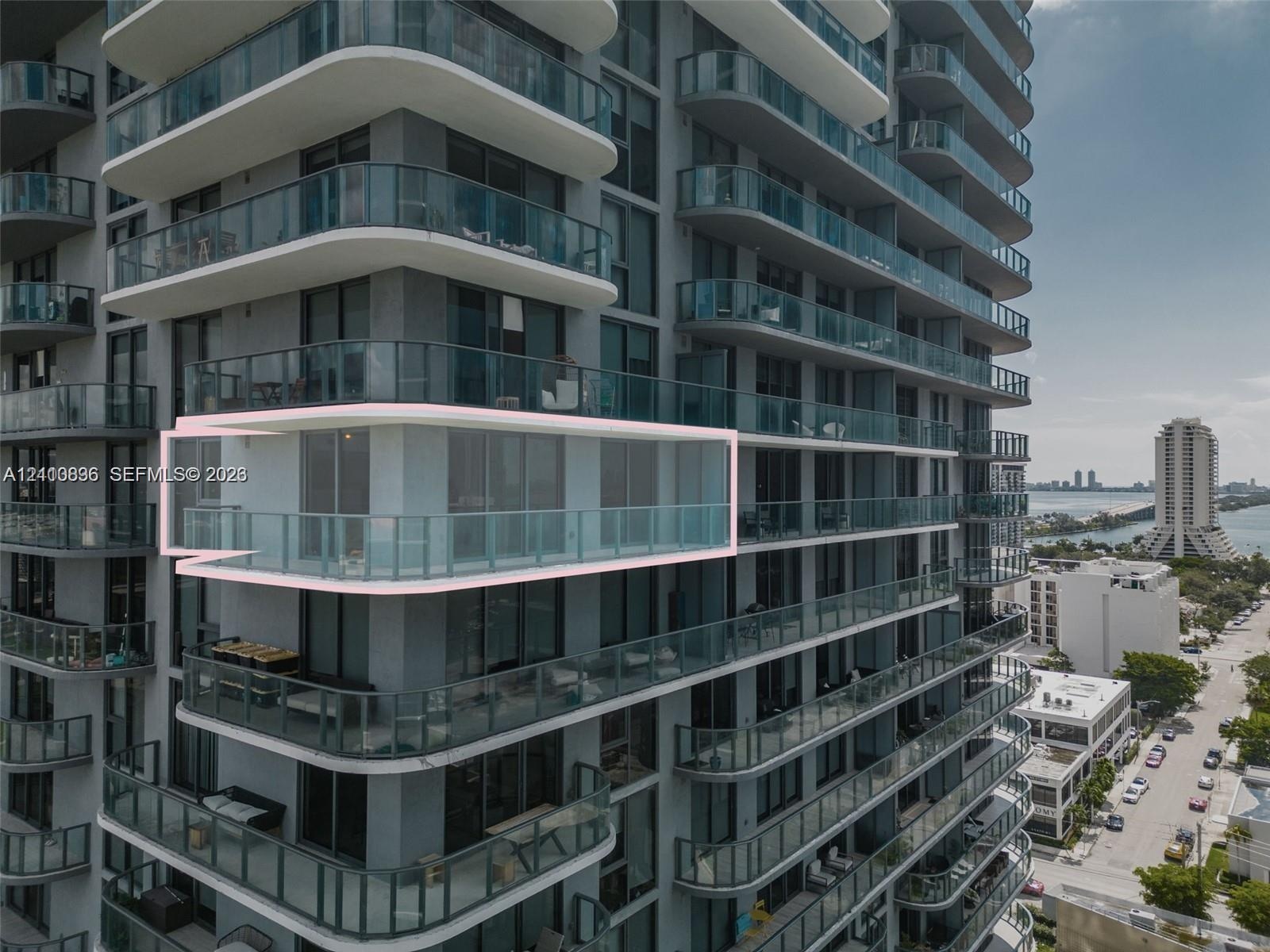 Modern high-rise residential tower featuring curved glass balconies, floor-to-ceiling windows, and streamlined white architectural trim