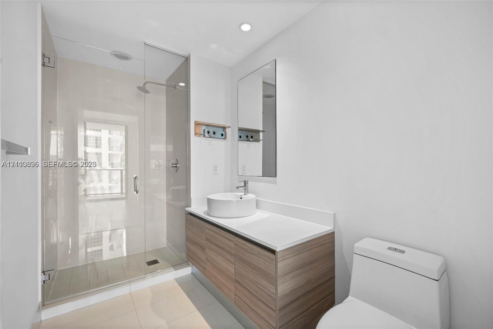 Bathroom featuring a wood-finish floating vanity, circular vessel sink, white solid-surface countertop, and a walk-in glass-enclosed shower with polis