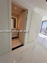 Large-format tile flooring, flush-mounted interior doors, and recessed ceiling lighting, with entry to a bathroom featuring a floating vanity and an i