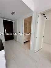 Entry foyer featuring high-gloss tile flooring, solid dark-wood entry door, and recessed lighting