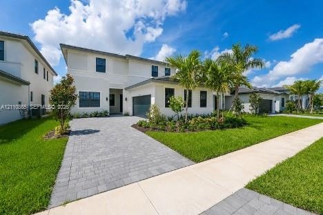 Two-story residence featuring a light-toned exterior, paved driveway, multi-pane windows, attached garage, and landscaped front lawn with palm trees