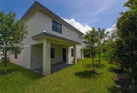 Two-story exterior featuring a covered patio, paved hardscaping, and landscaped green space