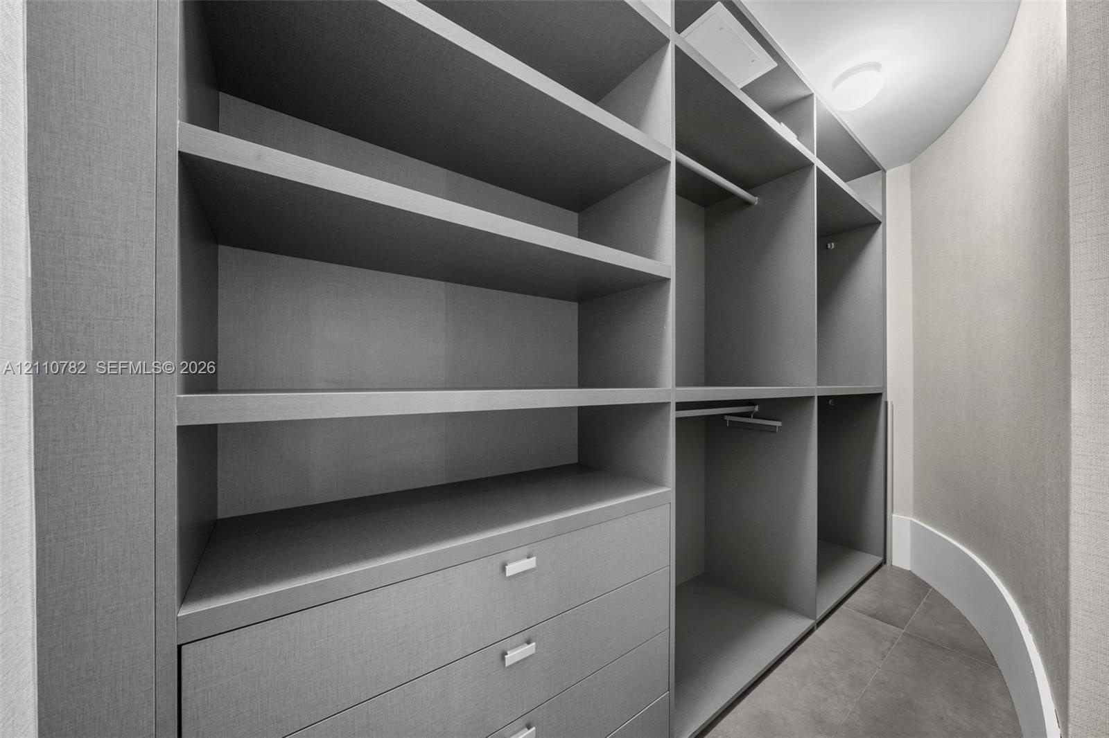 Custom organizational system featuring floor-to-ceiling cabinetry, integrated shelving, hanging rods, and built-in drawers with metallic hardware, set