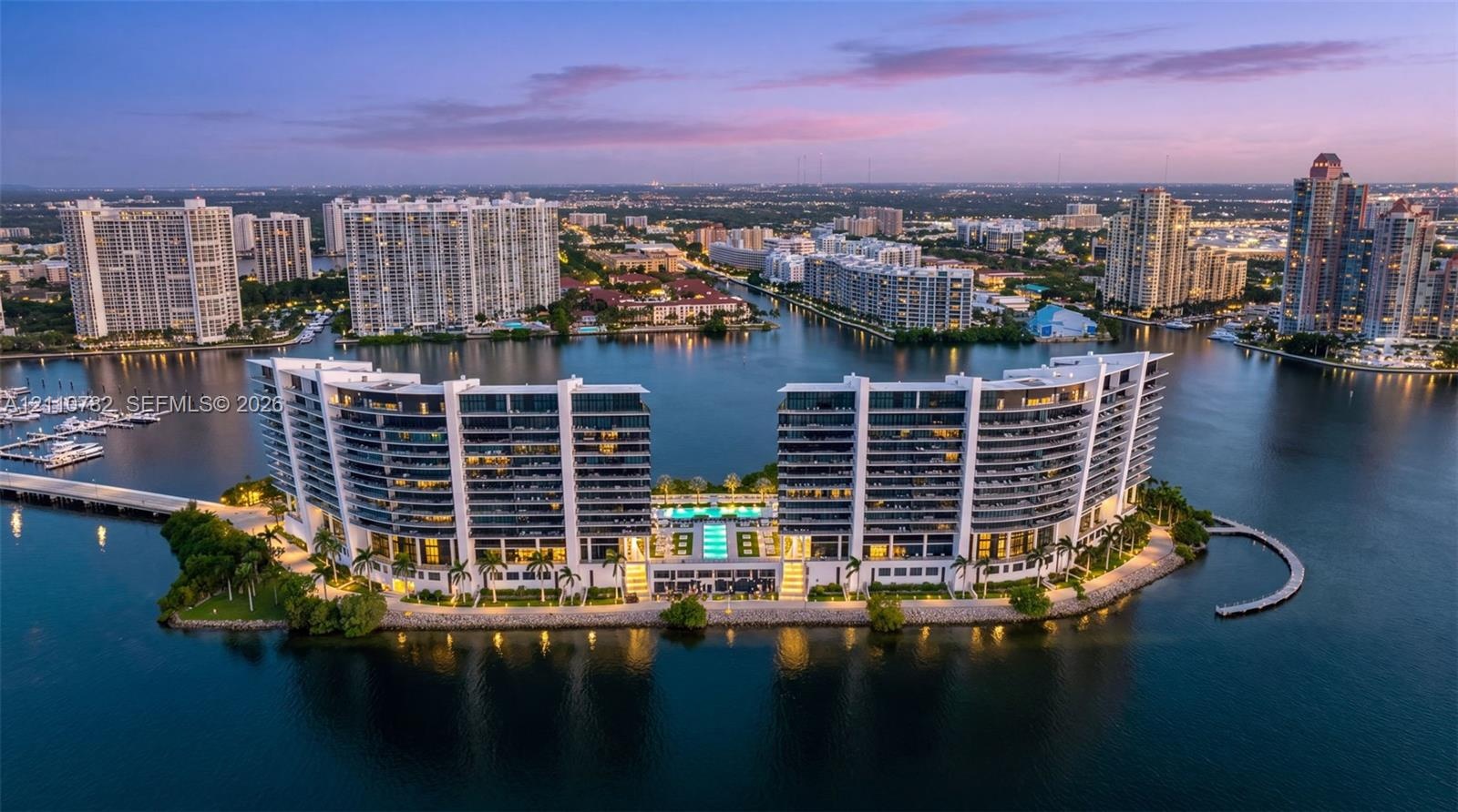 Waterfront high-rise complex featuring private swimming pools, palm-lined landscaping, and deep-water marina access