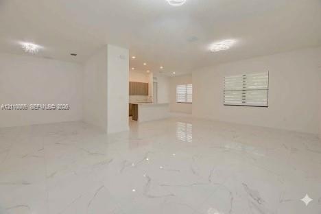 Open-concept interior featuring large-format tile flooring with veined detailing, recessed ceiling lighting, decorative flush-mount fixtures, and wind