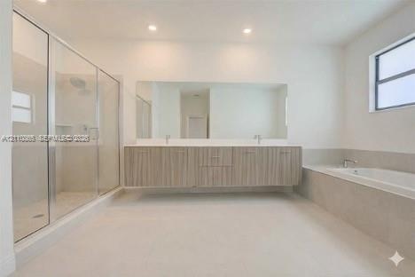 Floating vanity with double under-mount sinks, expansive wall-to-wall mirror, glass-enclosed walk-in shower, built-in soaking tub with stone surround,