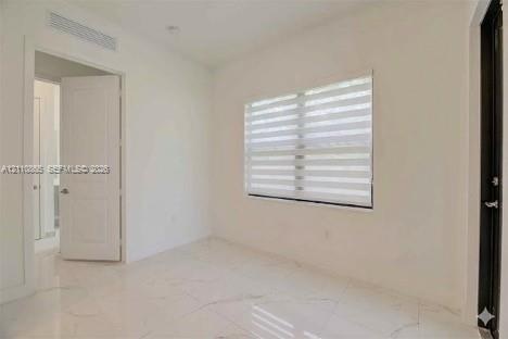 Interior space featuring light-toned stone-finish flooring, dual-panel interior door, banded window shades, and minimalist trim