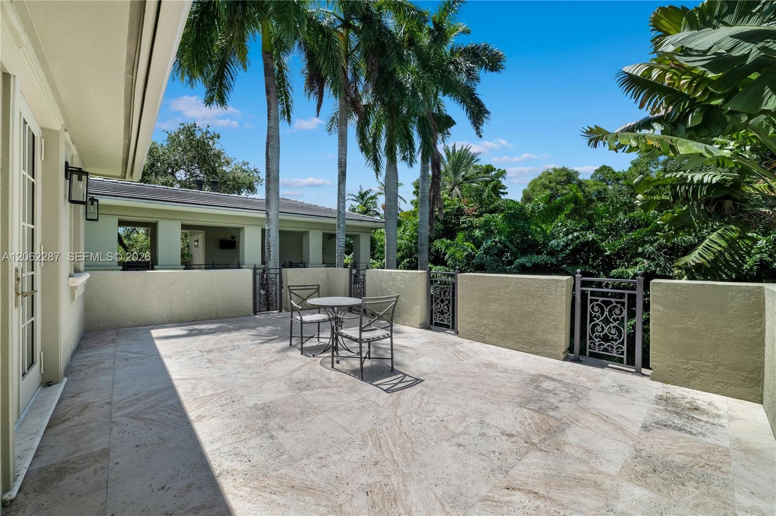Expansive upper patio stone-paved terrace featuring solid masonry perimeter walls and decorative wrought-iron railing accents