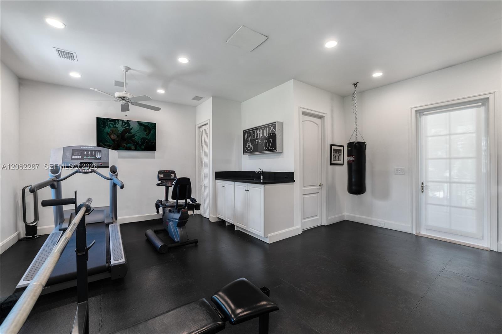 Interior space featuring recessed lighting, a ceiling fan, matte-finish flooring, built-in cabinetry with a stone countertop, and a glass-paneled exte