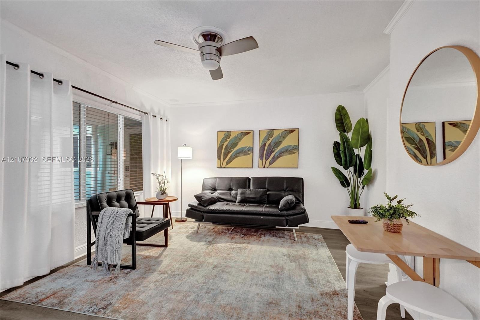 Living area featuring neutral wall paint, wood-finish flooring, crown molding, and a modern ceiling fan