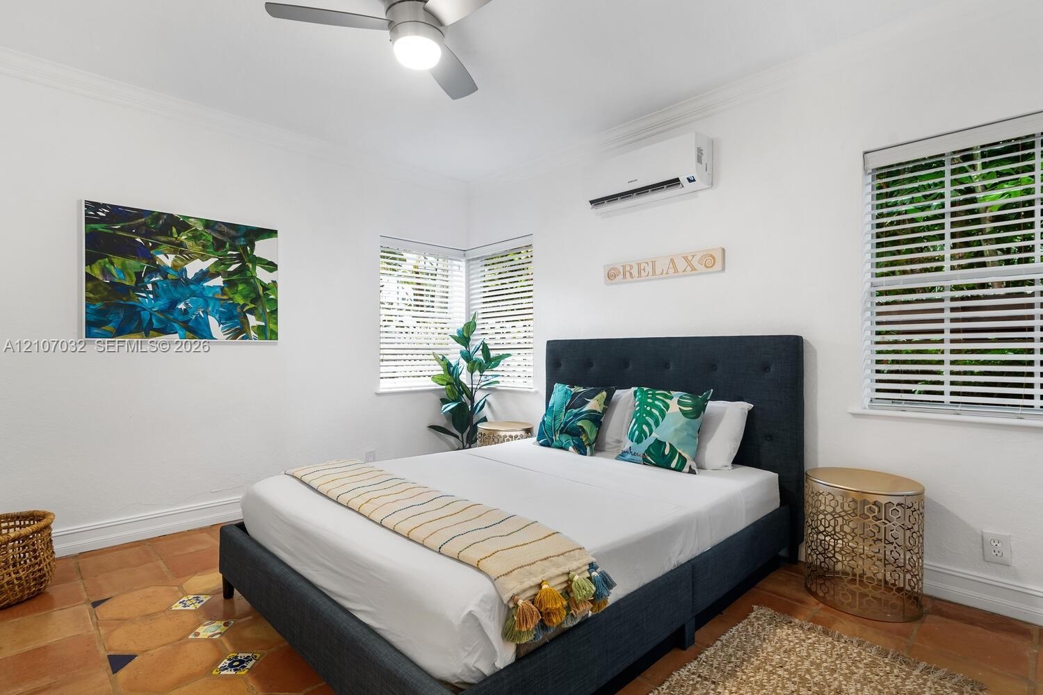 Room featuring terra-cotta tile flooring with decorative inlay accents, multi-pane windows with integrated blinds, ceiling fan, and wall-mounted clima
