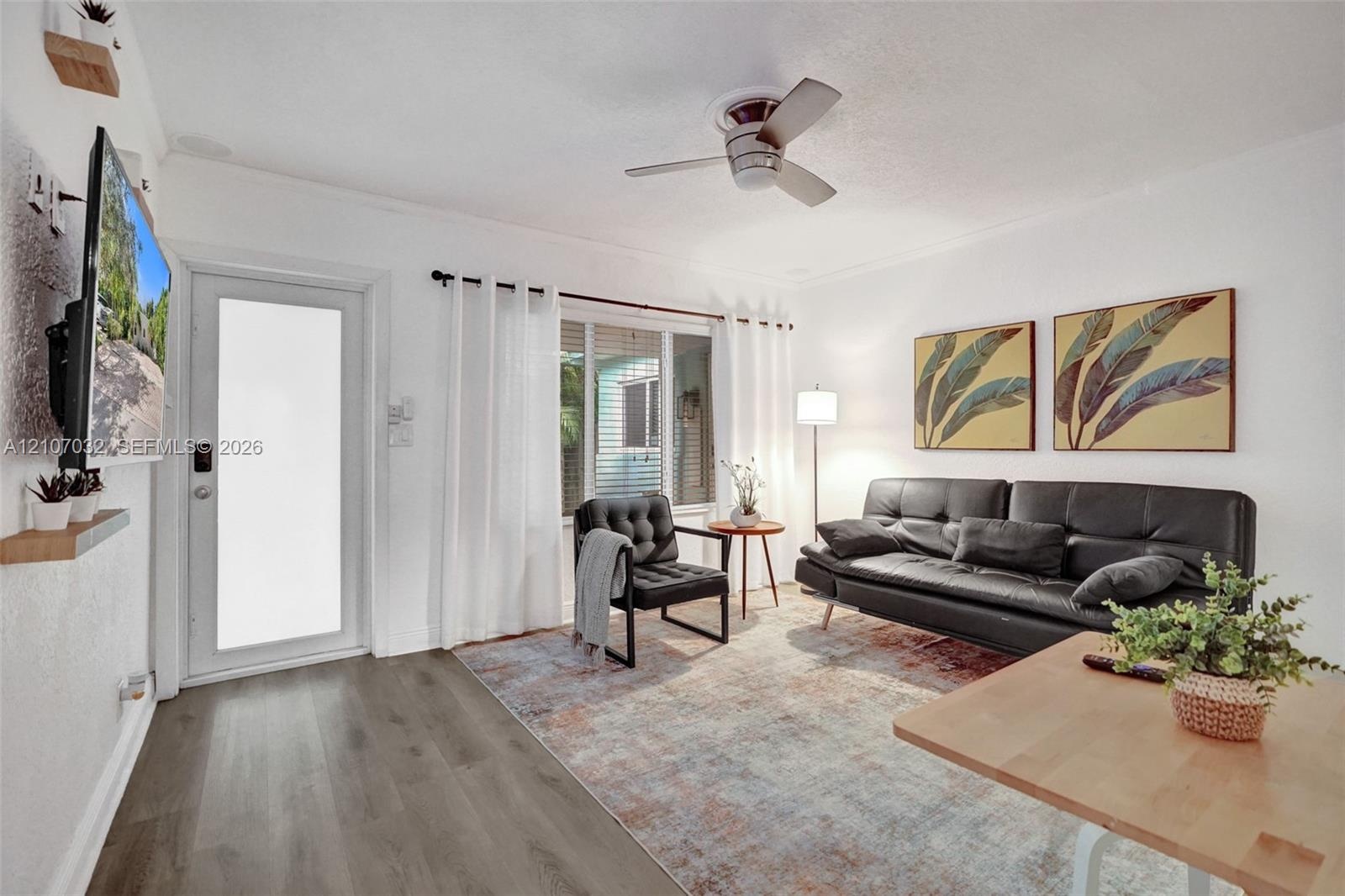 Living area featuring wood-finish flooring, a ceiling fan, and a glass-panel exterior door