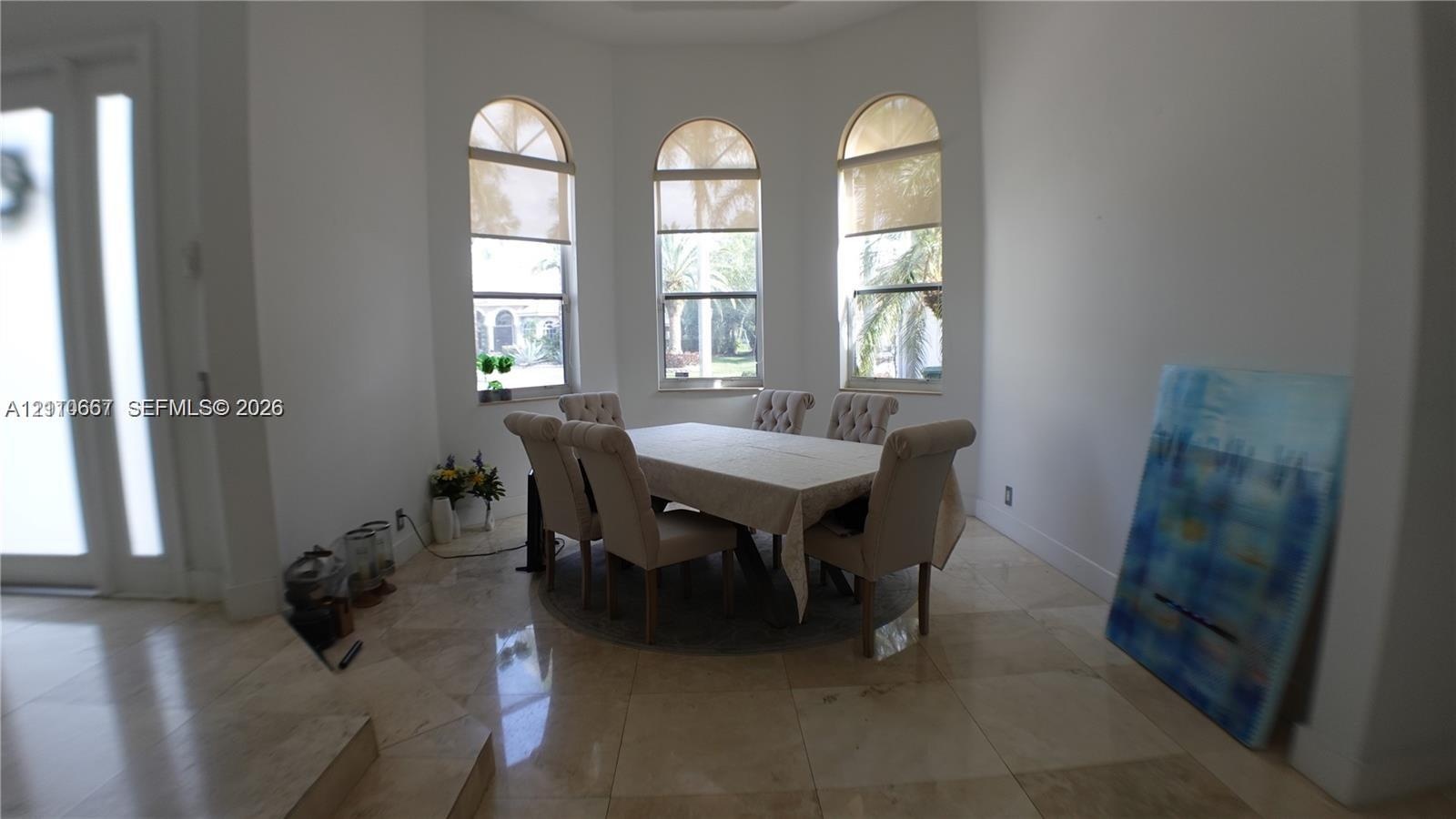 Arched windows, bay window configuration, and polished stone tile flooring