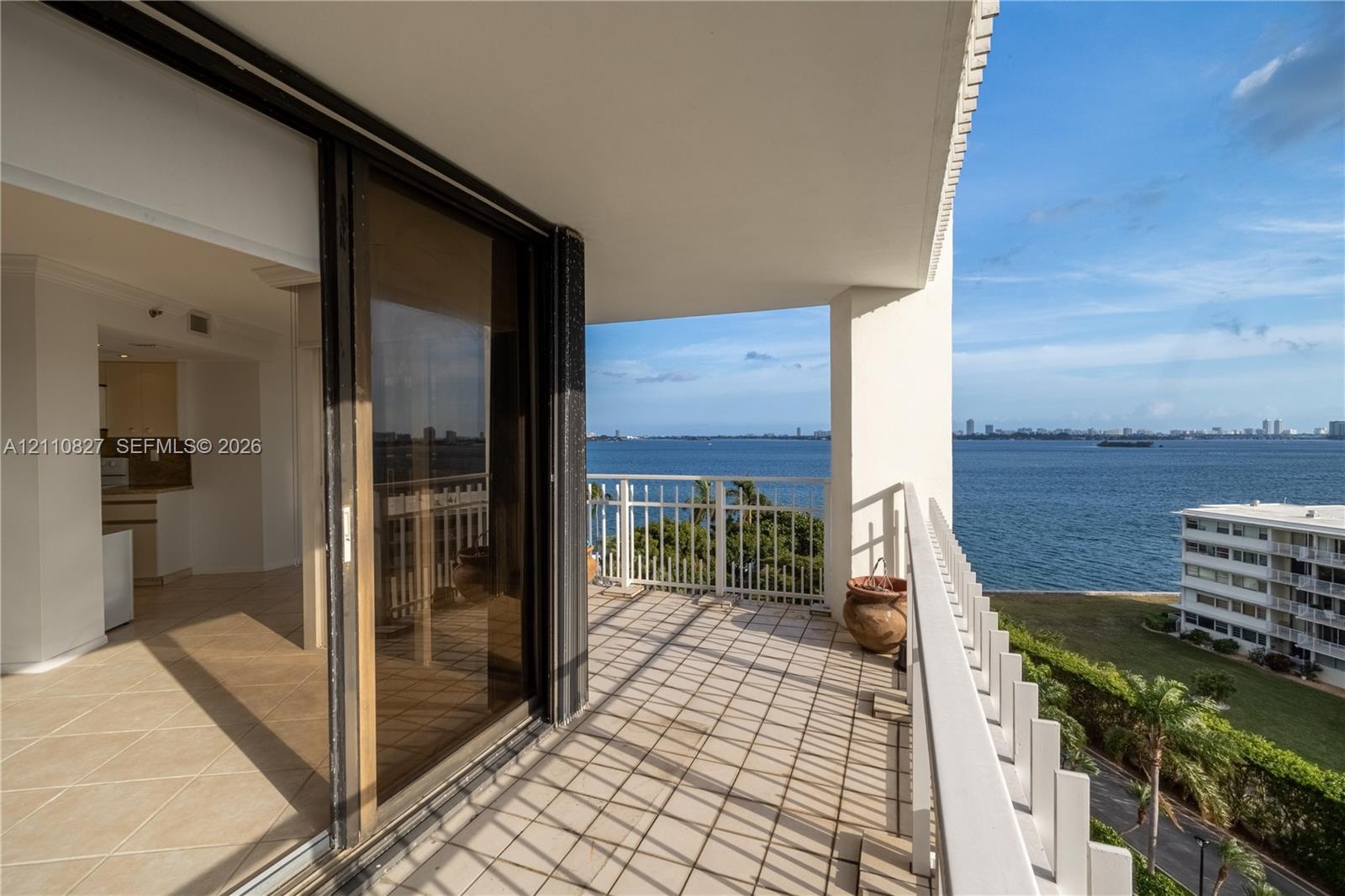 Covered balcony featuring tile flooring and a metal railing with water frontage