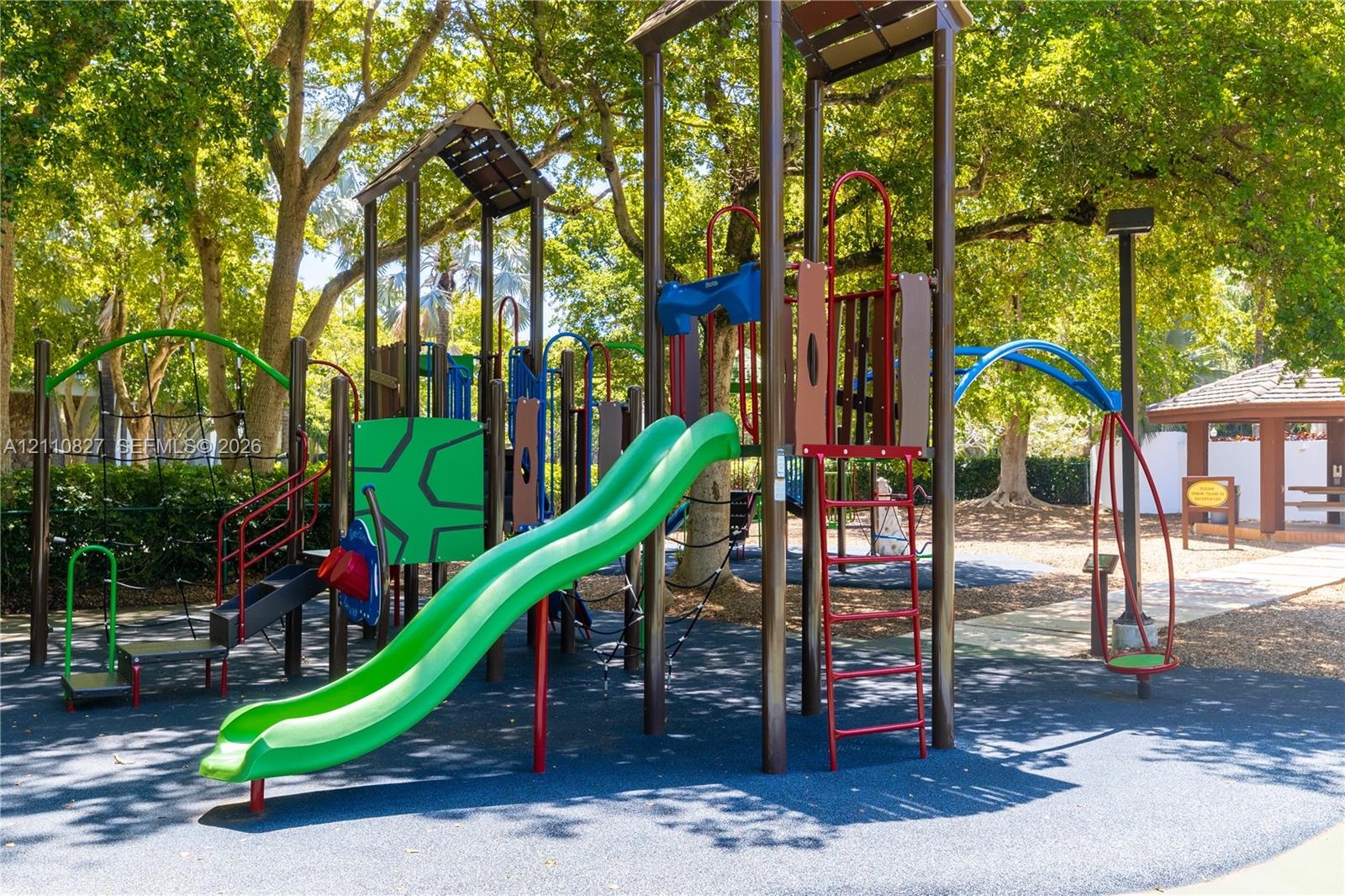 Outdoor recreation area featuring a multi-level playground structure, integrated slide, climbing apparatus, and protective rubberized flooring