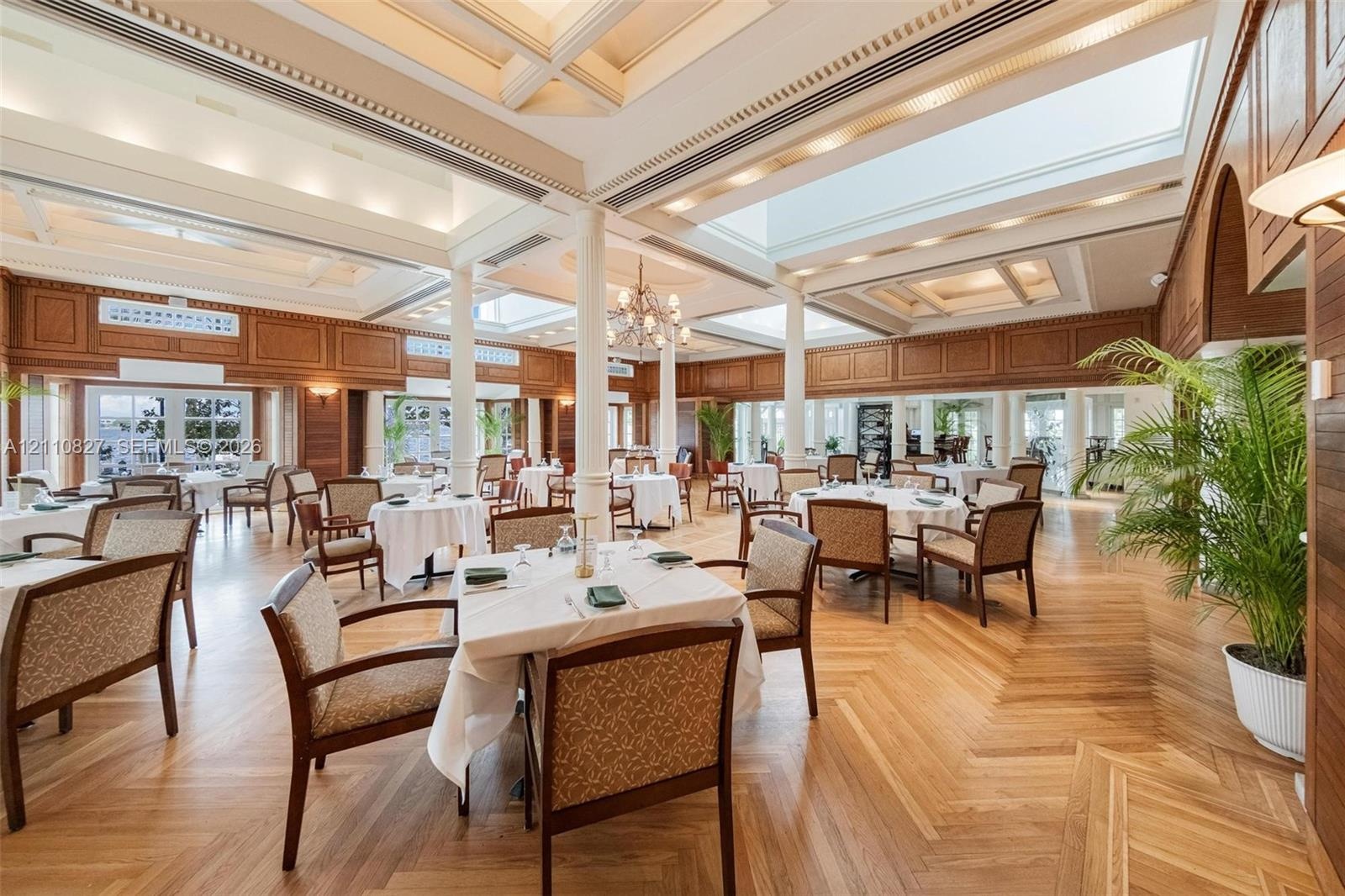 Expansive interior space featuring coffered ceilings, skylights, intricate wall paneling, structural columns, and herringbone-pattern wood-finish floo