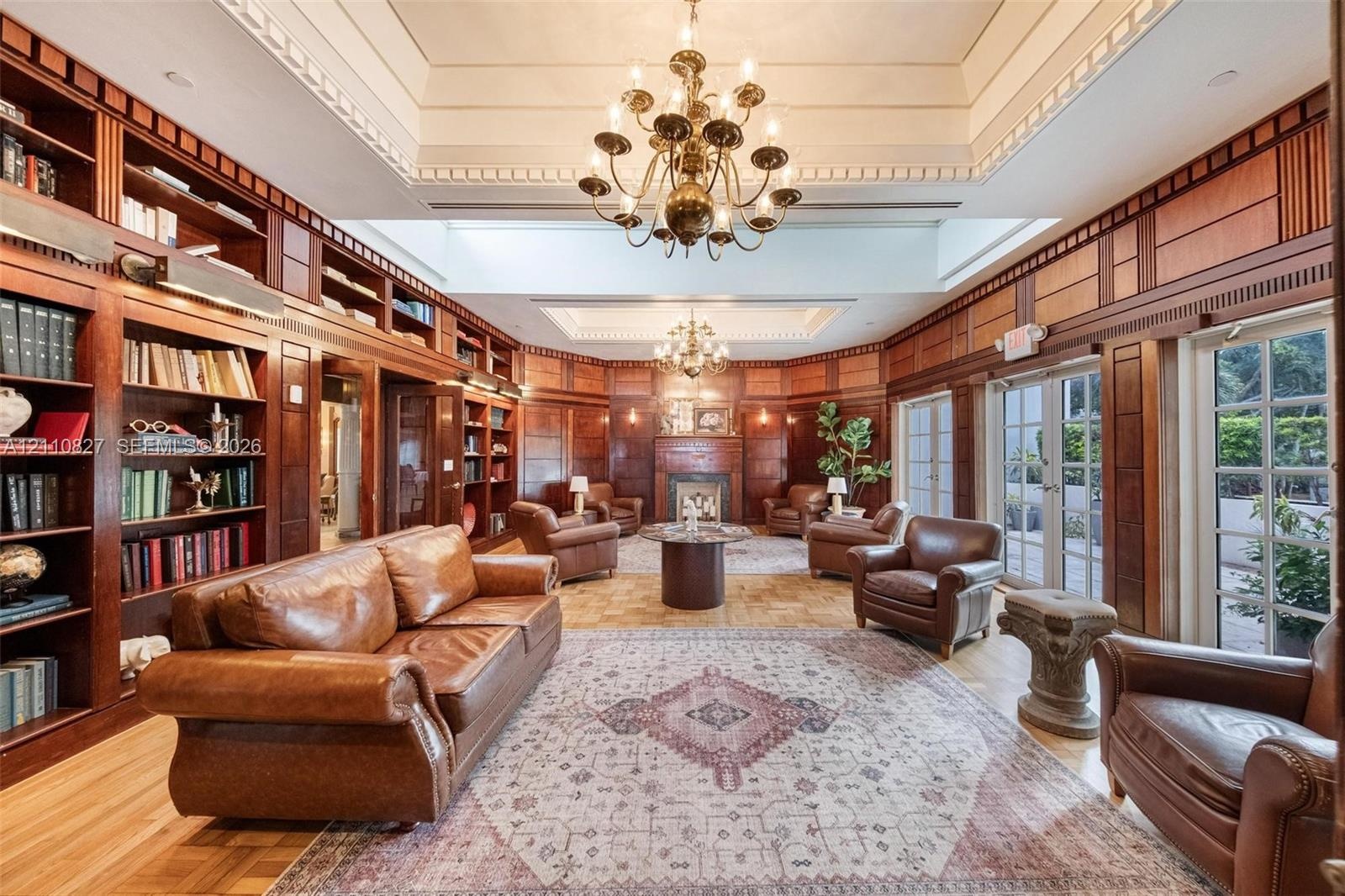Extensive floor-to-ceiling wood paneling, built-in library shelving, dual tiered tray ceilings with decorative millwork, multiple sets of glass-panele