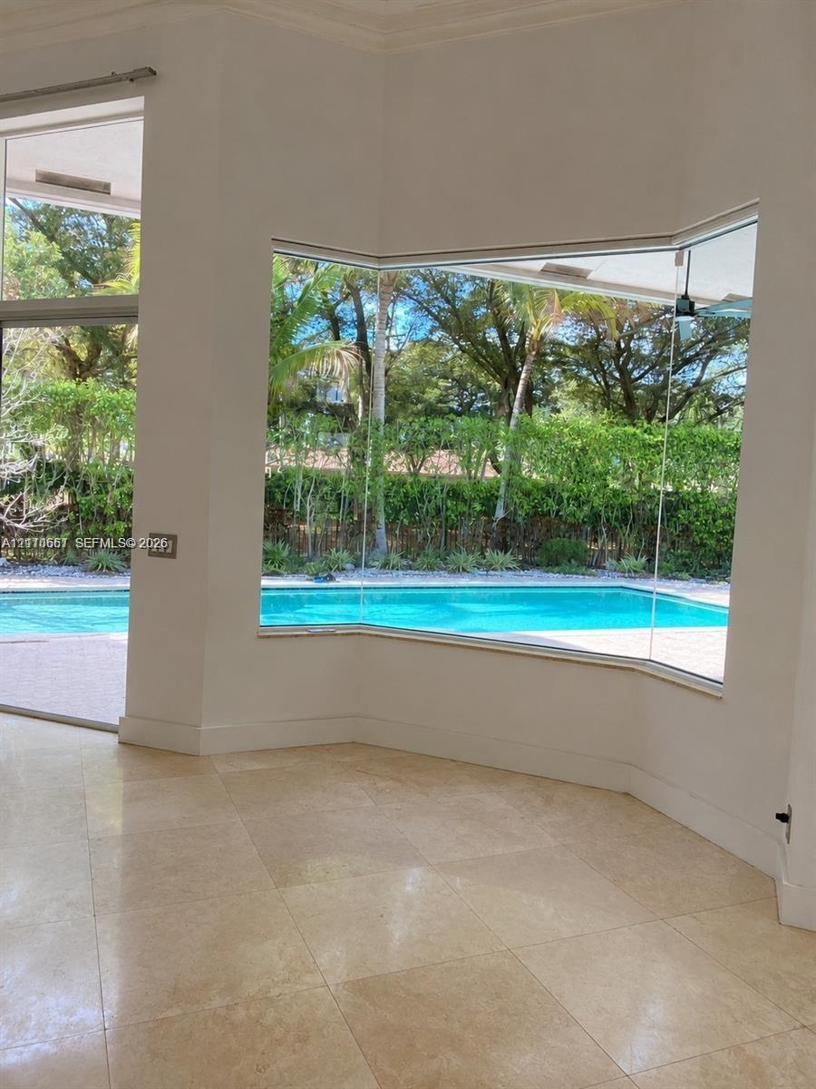 Large bay windows featuring expansive glass panels, stone-finish tile flooring, and direct exterior exposure to a swimming pool and landscaped grounds