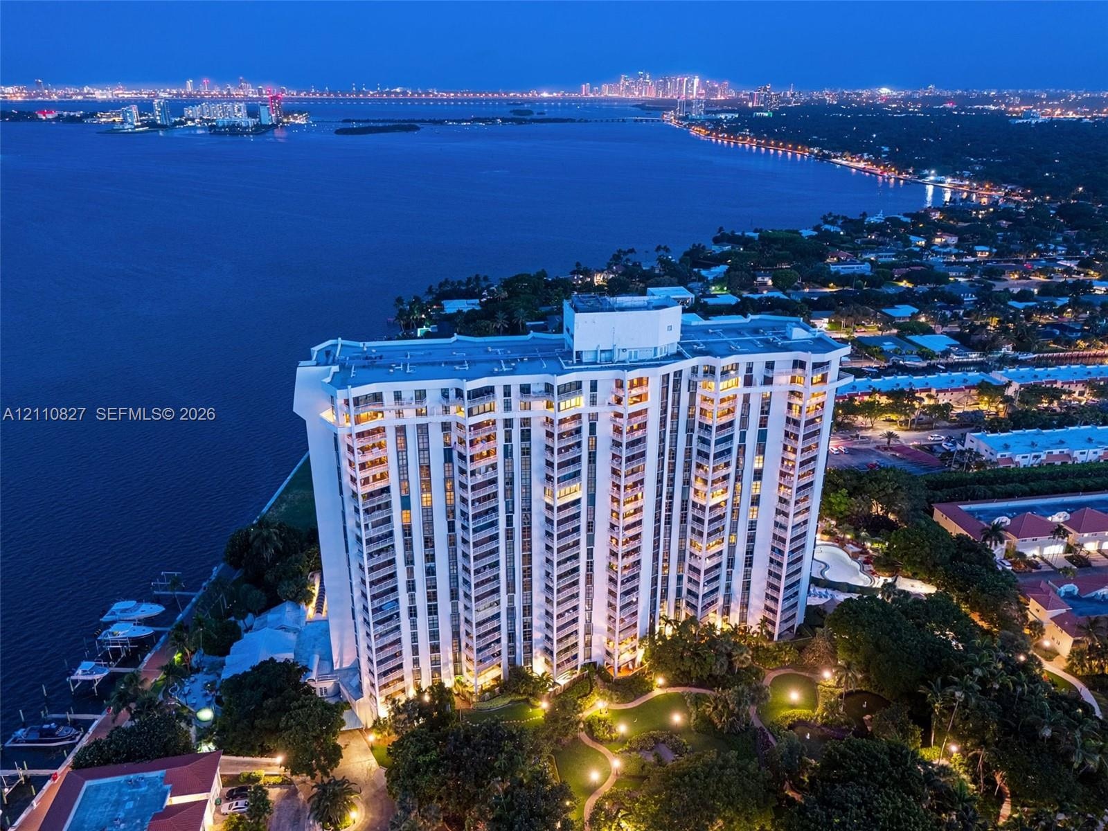 High-rise building featuring private boat slips, landscaped grounds, a paved walking path, and waterfront positioning