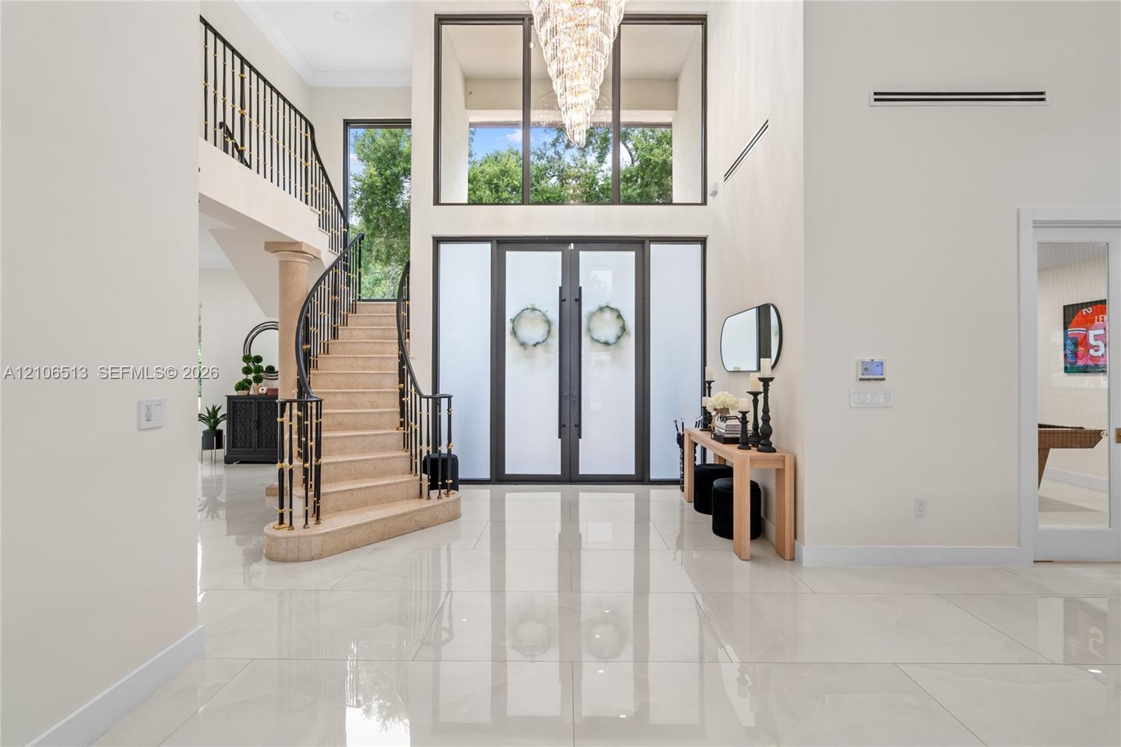 Grand foyer featuring polished large-format tile flooring, double entry doors with frosted glass panels, an expansive multi-story window, a tiered cry