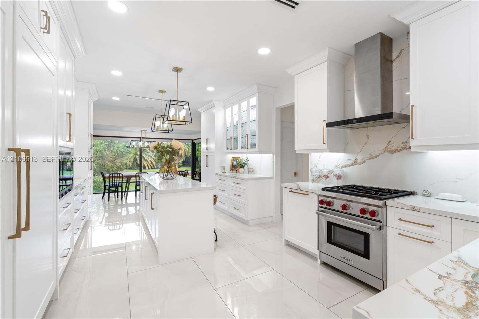 Kitchen featuring white Shaker-style cabinetry, a central island with a stone-finish countertop, stainless steel professional-grade range, full-height