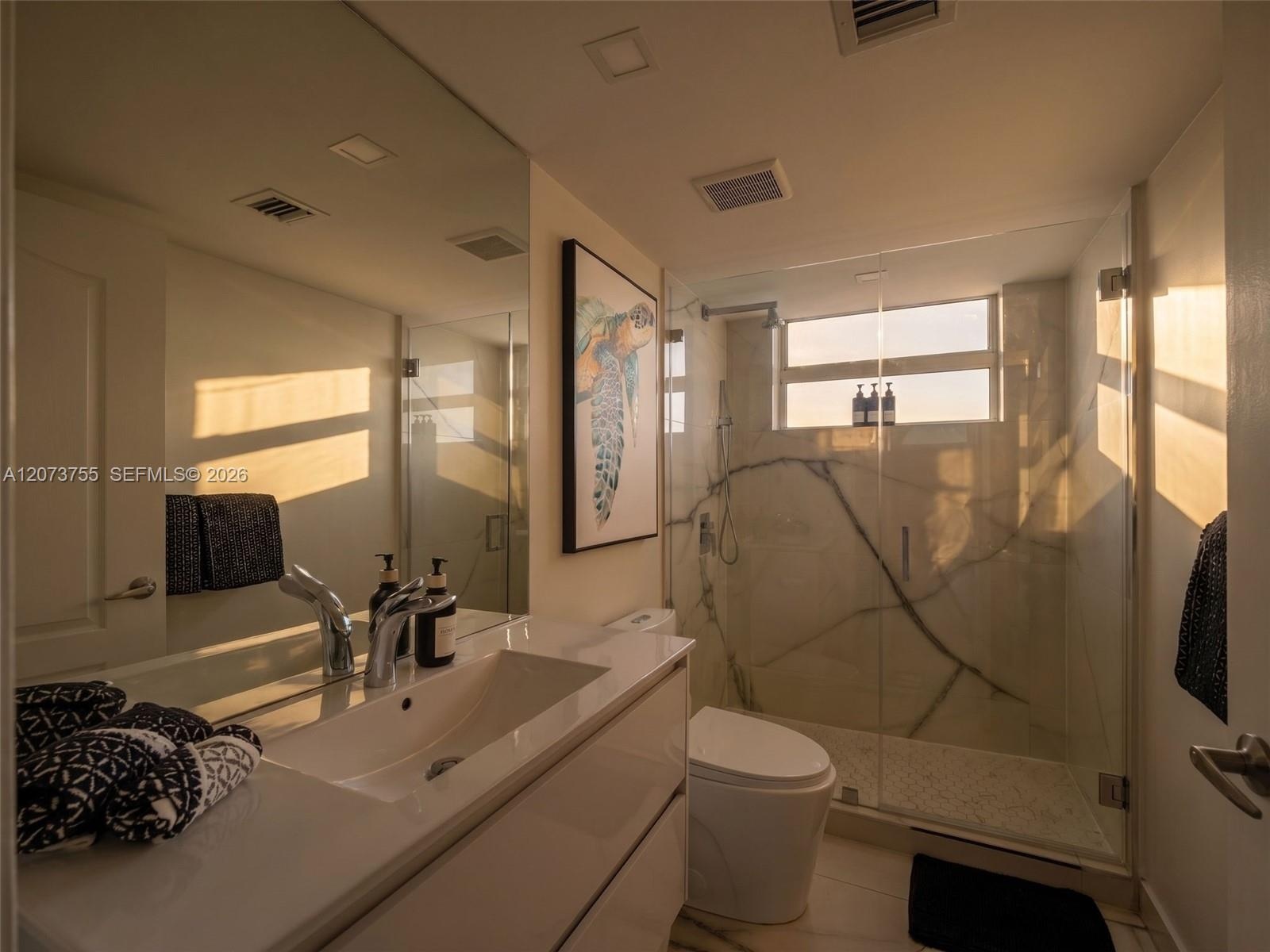 Floating vanity with an integrated rectangular sink, wall-spanning mirror, and a walk-in shower featuring large-format veined wall tile and a glass en